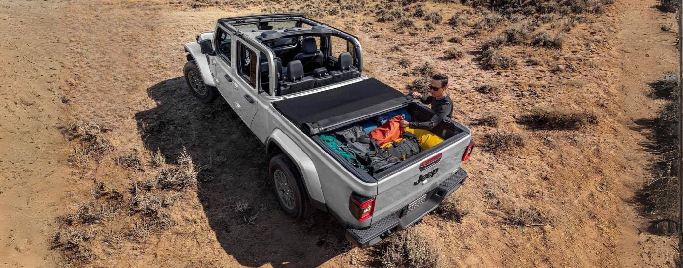 A person getting equipment out of the bed of their white 2024 Jeep Gladiator