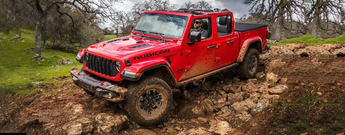 A red 2024 Jeep Gladiator Rubicon off-roading on rocks