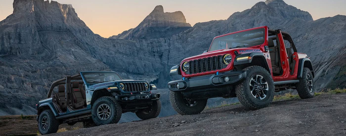 A red and a grey 2026 Jeep Wrangler parked with a mountain view