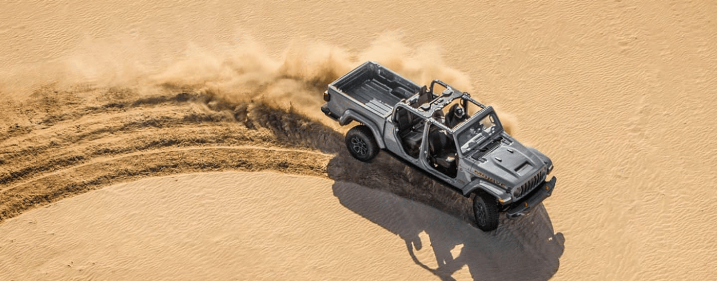 Silver 2026 Jeep Gladiator drifting around a sand dune