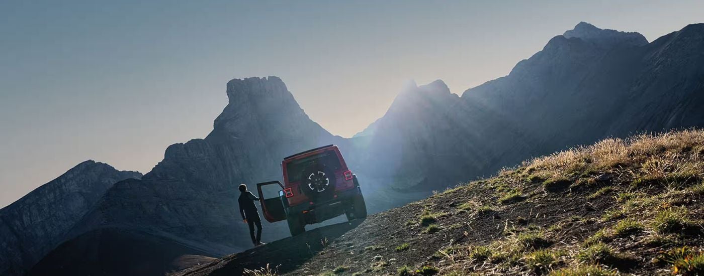 Red 2026 Jeep Wrangler off-roading in the mountains.