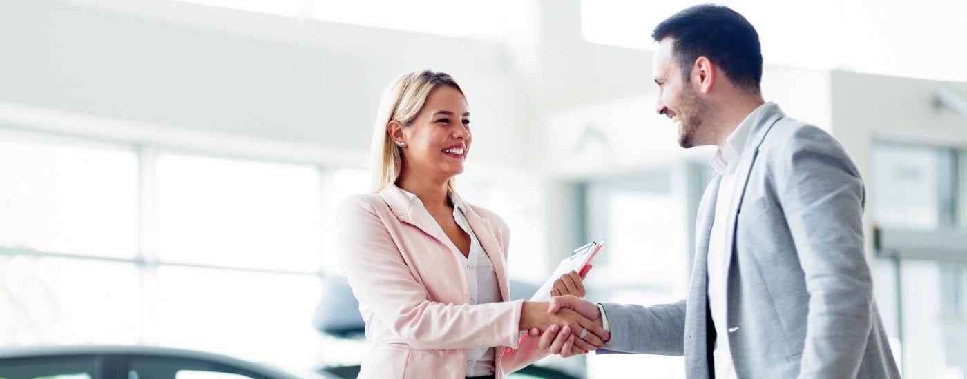 People shaking hands at a car dealership